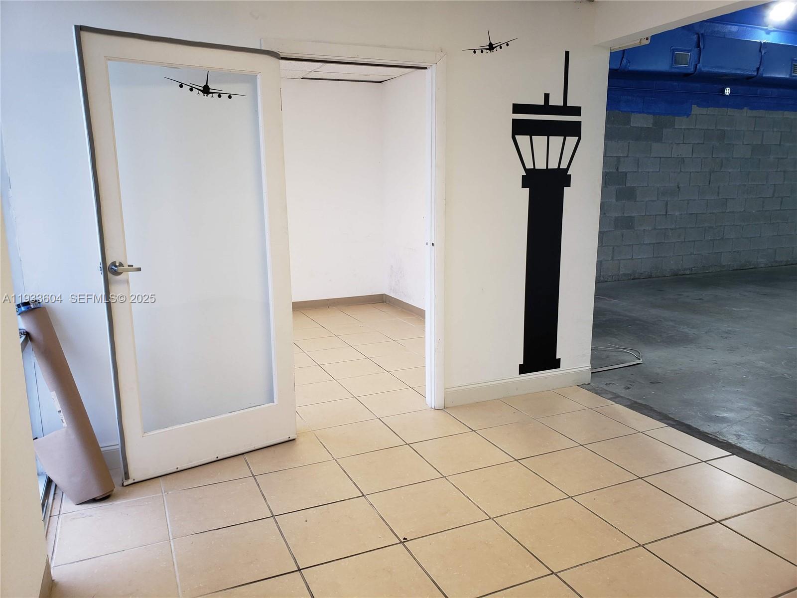 An interior view shows a tiled room with an open doorway and a control tower decal — 13491 NW 47th Ave # 2, Opa-Locka FL 33054, OPA-LOCKA, FL