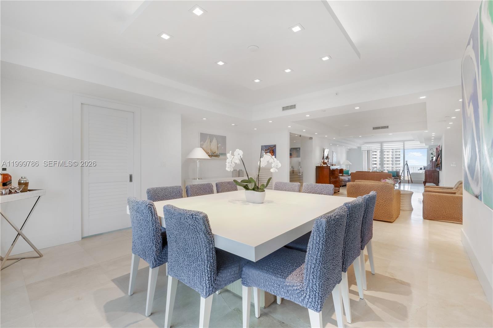 A bright dining area features a large square white table with blue textured chairs — 789 Crandon Blvd # 1003, Key Biscayne FL 33149, KEY BISCAYNE, FL