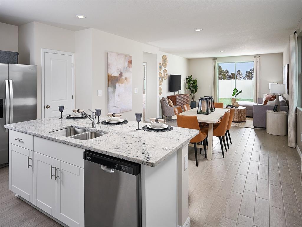 A kitchen island with granite countertops overlooks an open-concept dining area and living room — 3902 TEAK LANE, BARTOW, FL