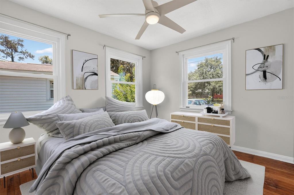 A bedroom features a bed with a gray patterned comforter, two windows, and a ceiling fan — 5503 LAKEWOOD CIRCLE E, JACKSONVILLE, FL