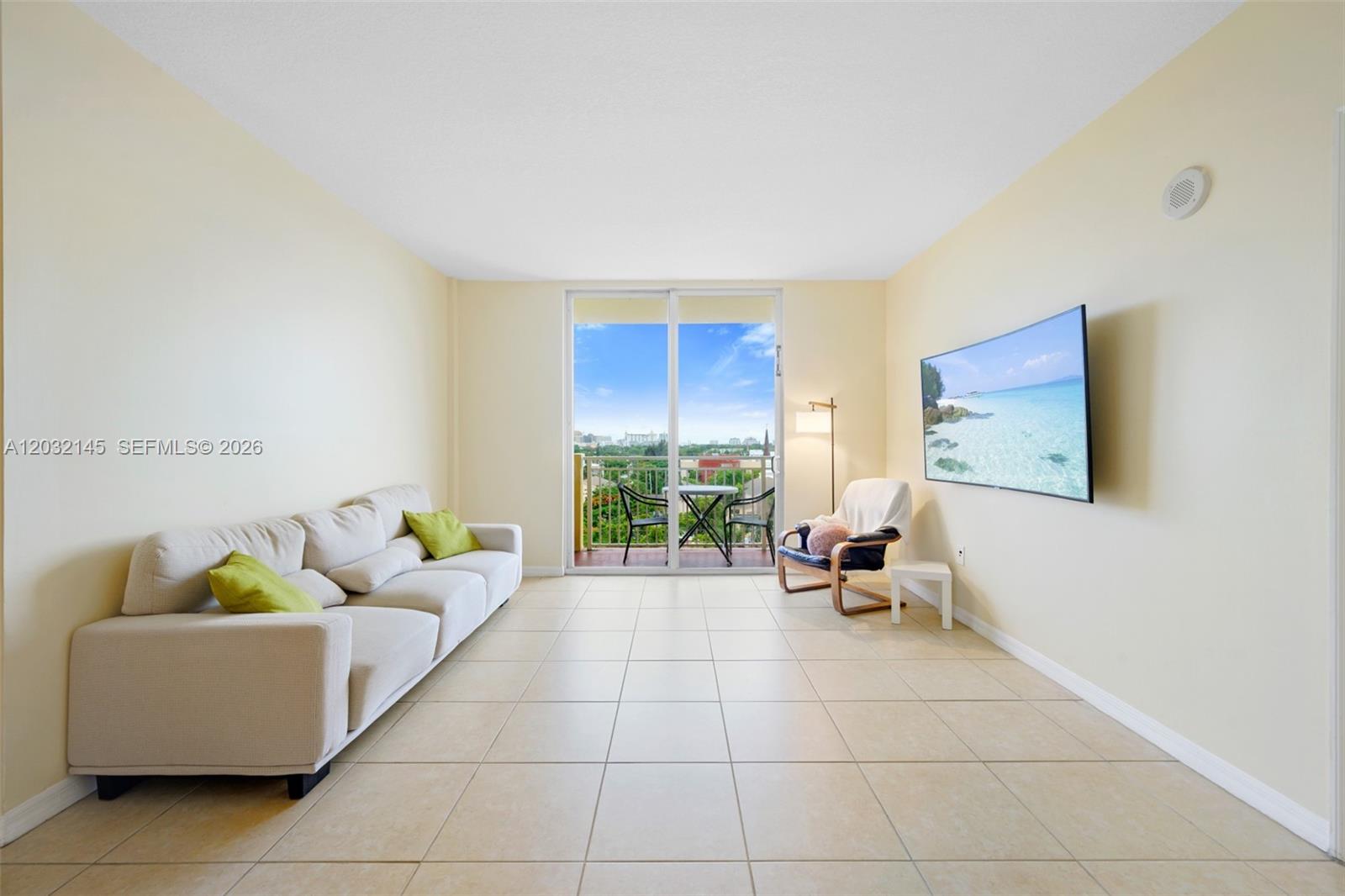 A living room features light tile flooring, a beige sofa, a wall-mounted television, and a balcony — 215 SW 42nd Ave # 708, Miami FL 33134, MIAMI, FL