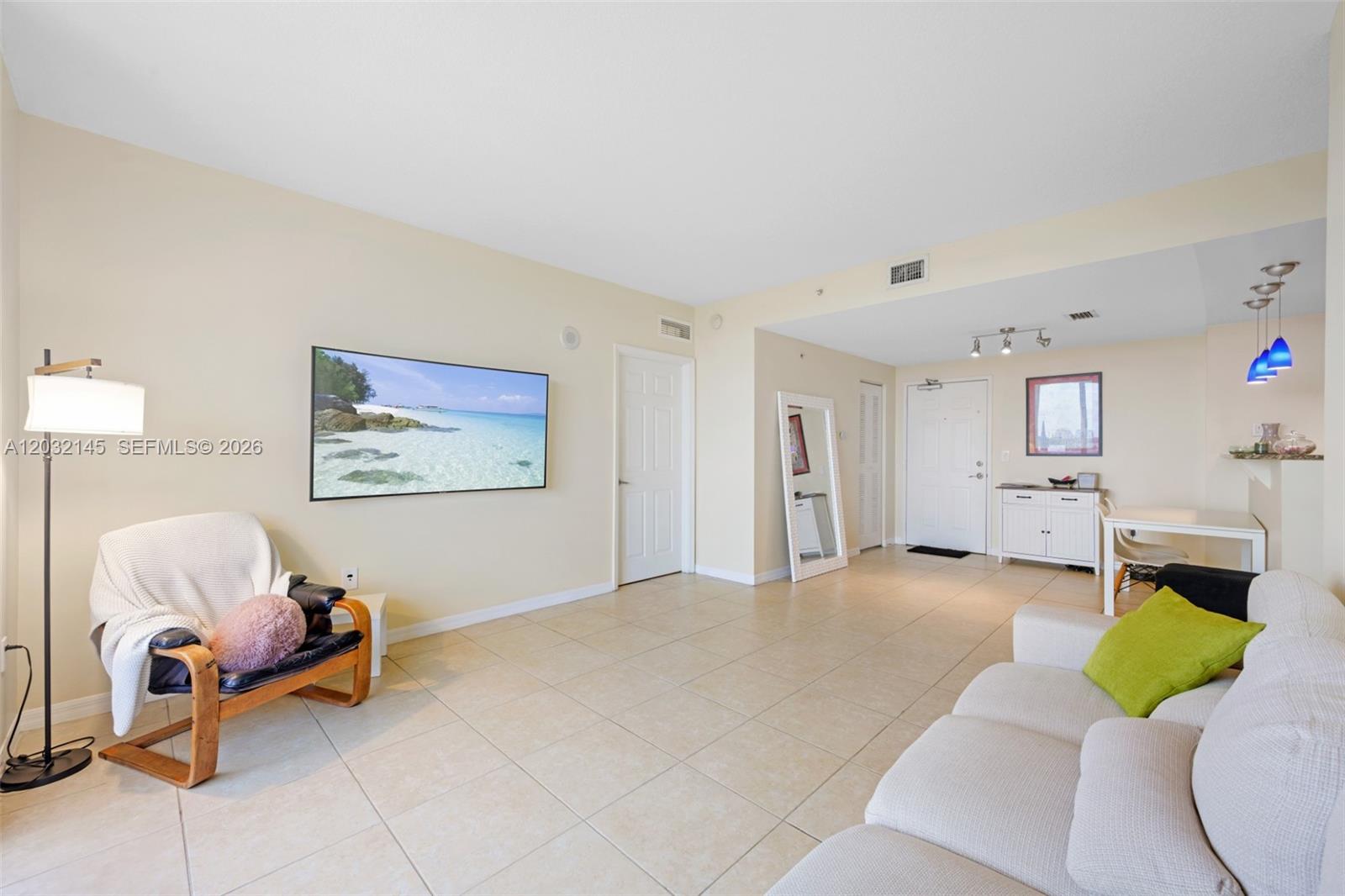 A living room features beige tile floors, a wall-mounted television, and a white sofa — 215 SW 42nd Ave # 708, Miami FL 33134, MIAMI, FL