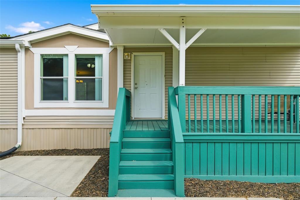 A white front door with teal wooden stairs and a matching deck under a porch — 2564 N CREDE AVENUE, CRYSTAL RIVER, FL