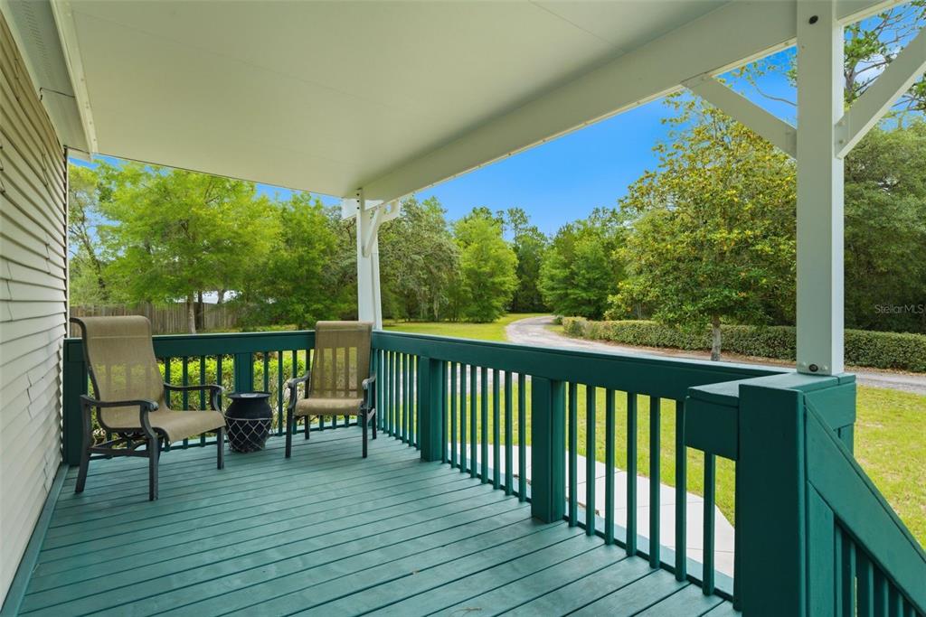 A covered wooden porch with green railings and two chairs overlooks a grassy yard — 2564 N CREDE AVENUE, CRYSTAL RIVER, FL