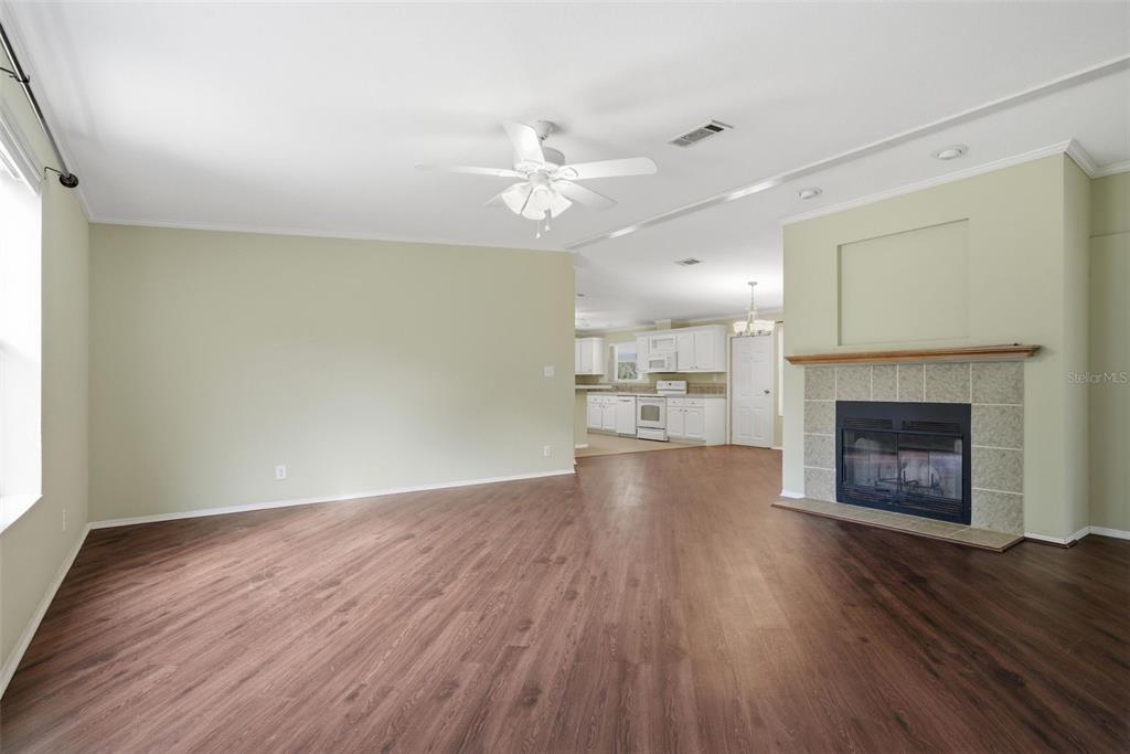 A living room with wood-look flooring, a ceiling fan, and a fireplace with tile surround — 2564 N CREDE AVENUE, CRYSTAL RIVER, FL