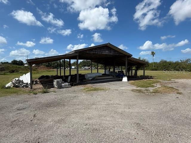 An open-sided wooden pole barn stands on a gravel lot under a blue sky — 2203 42ND STREET E, BRADENTON, FL