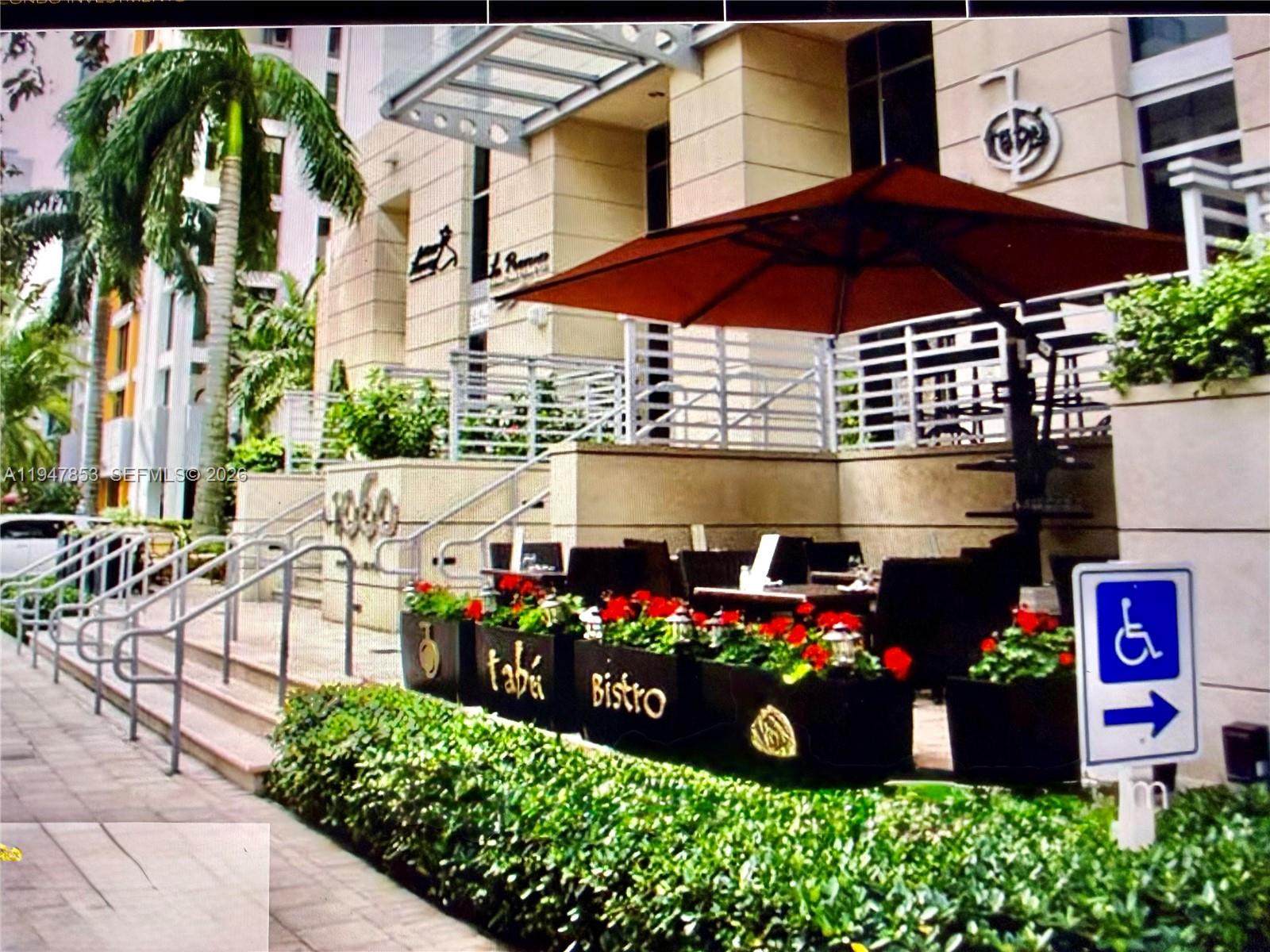 An outdoor patio area features tables, chairs, and planters with red flowers at a bistro — 1050 Brickell Ave # 1816, Miami FL 33131, MIAMI, FL