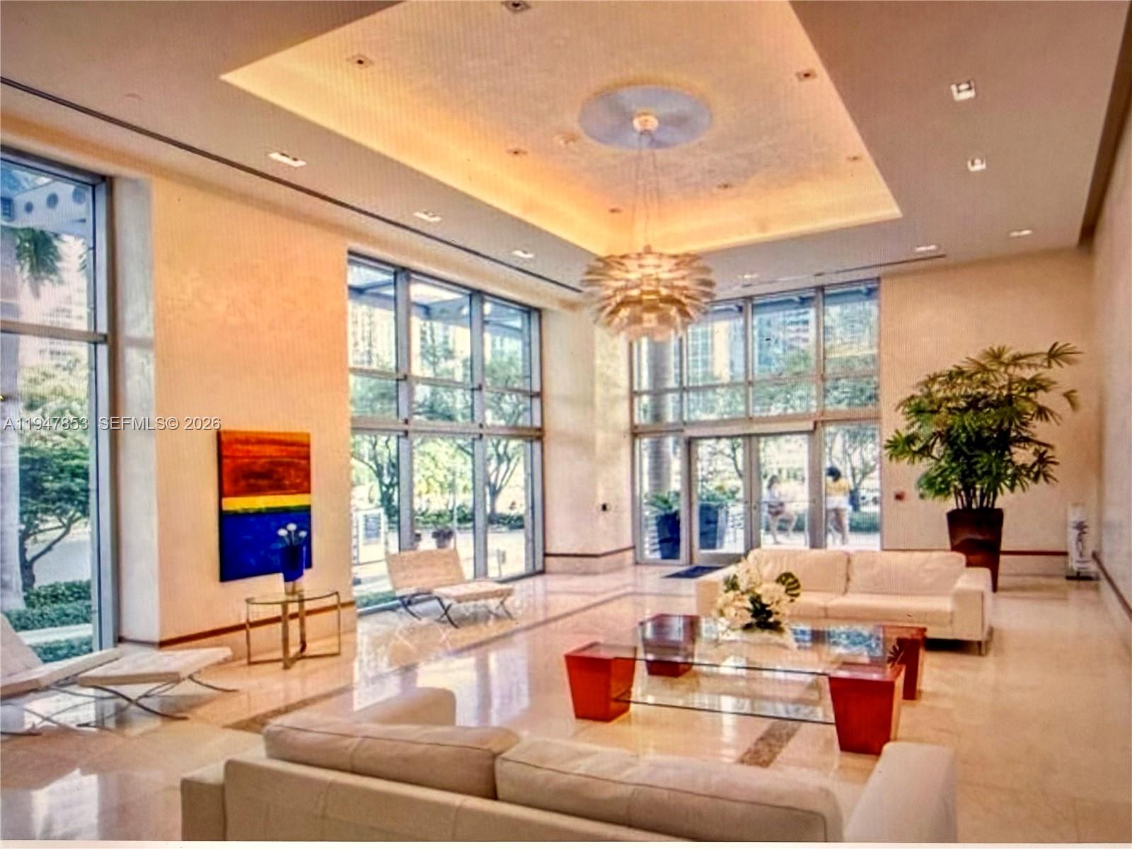 A bright, modern lobby features high ceilings, floor-to-ceiling windows, white sofas, and a glass table — 1050 Brickell Ave # 1816, Miami FL 33131, MIAMI, FL