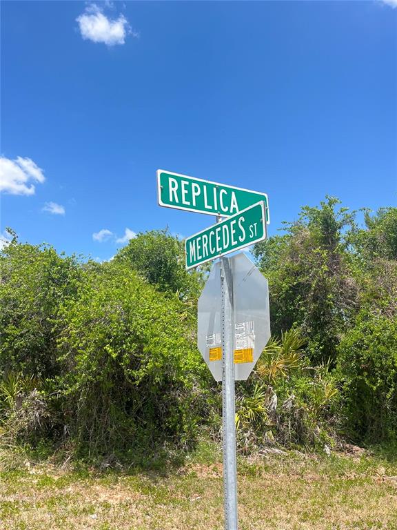 A street sign at the intersection of Replica and Mercedes Street stands before dense foliage — 901 REPLICA AVENUE, SEBRING, FL