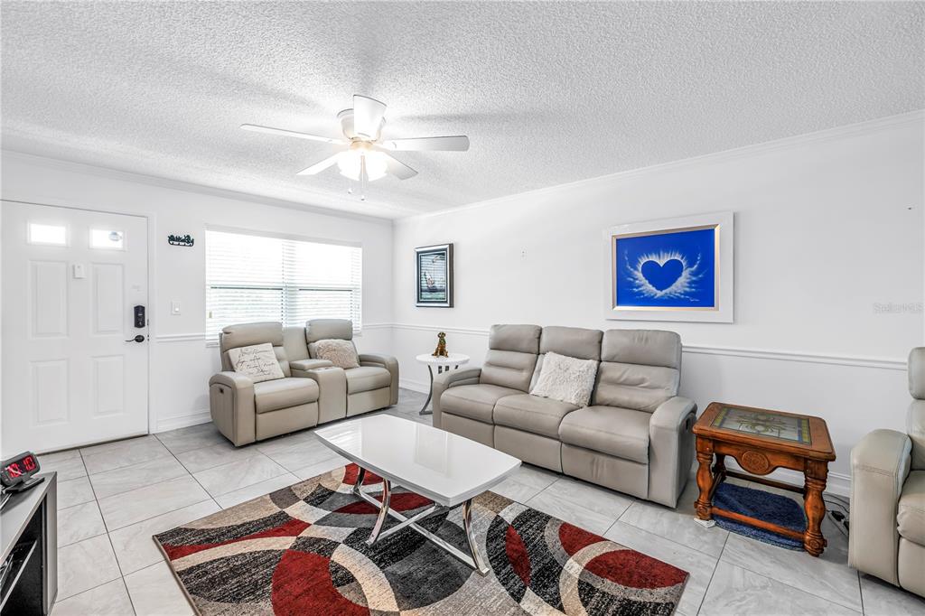 A living room features light gray leather furniture, a patterned area rug, and tile flooring — 6190 80TH STREET N UNIT 304, ST PETERSBURG, FL