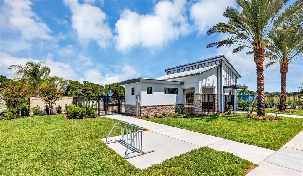 A modern community clubhouse building with a bike rack on a concrete walkway outdoors — 3117 ROCKWOOD WAY, MINNEOLA, FL