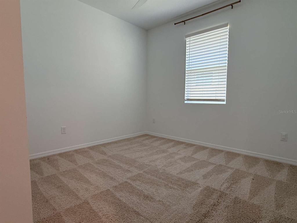 An empty bedroom features beige carpet, white walls, and a window with white blinds — 3081 AMBERSWEET PLACE, CLERMONT, FL