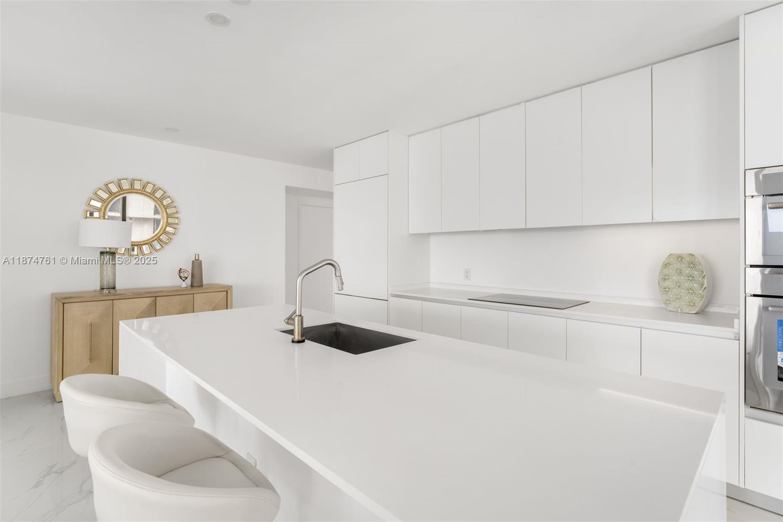 A modern white kitchen features a large island with a sink and bar seating — 700 NE 24th St # 2201, Miami FL 33137, MIAMI, FL