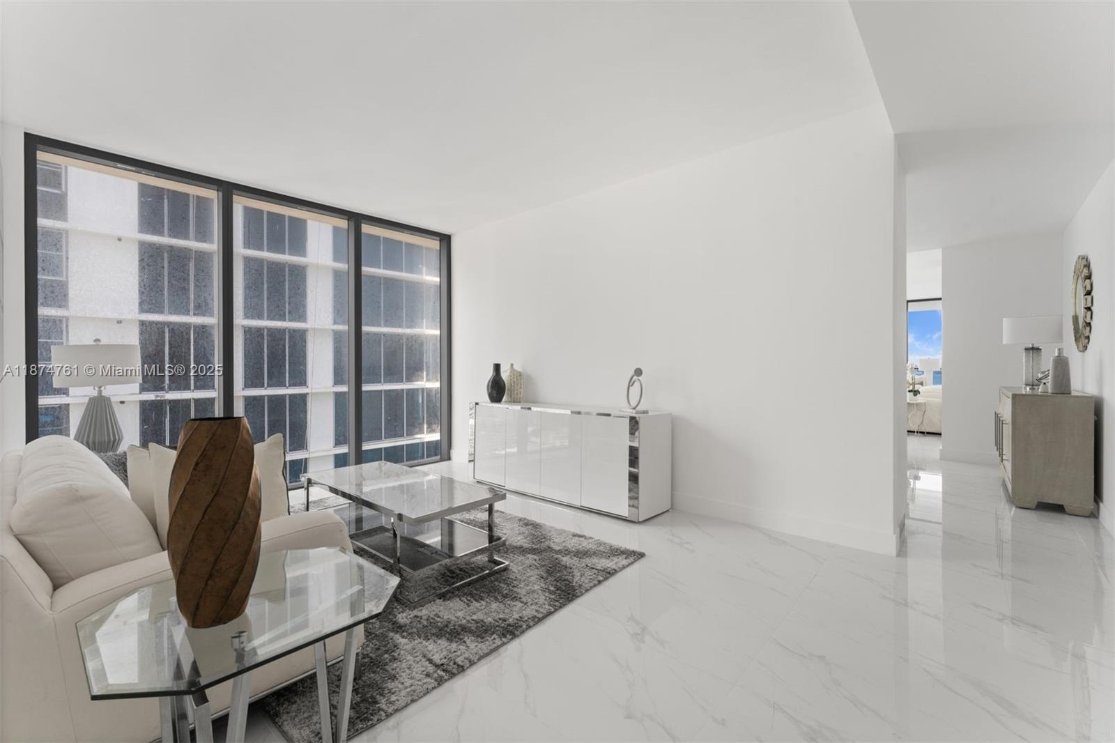 A modern living room features white marble floors, a glass coffee table, and floor-to-ceiling windows — 700 NE 24th St # 2201, Miami FL 33137, MIAMI, FL