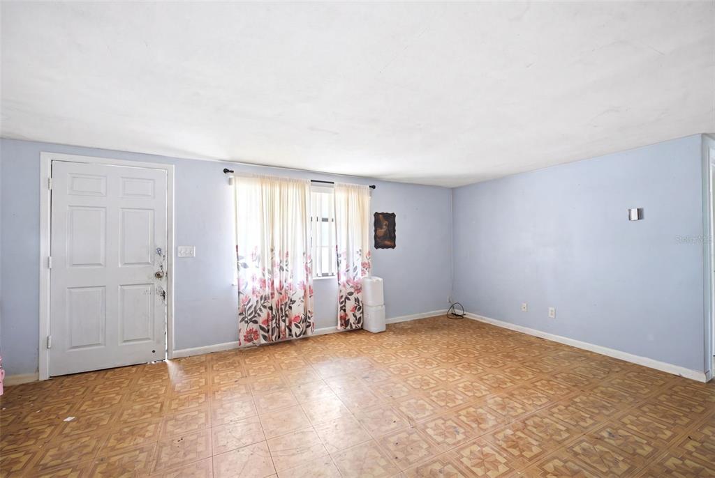 An empty room features light blue walls, patterned vinyl flooring, and a white entry door — 10 S JACKSON STREET, BEVERLY HILLS, FL