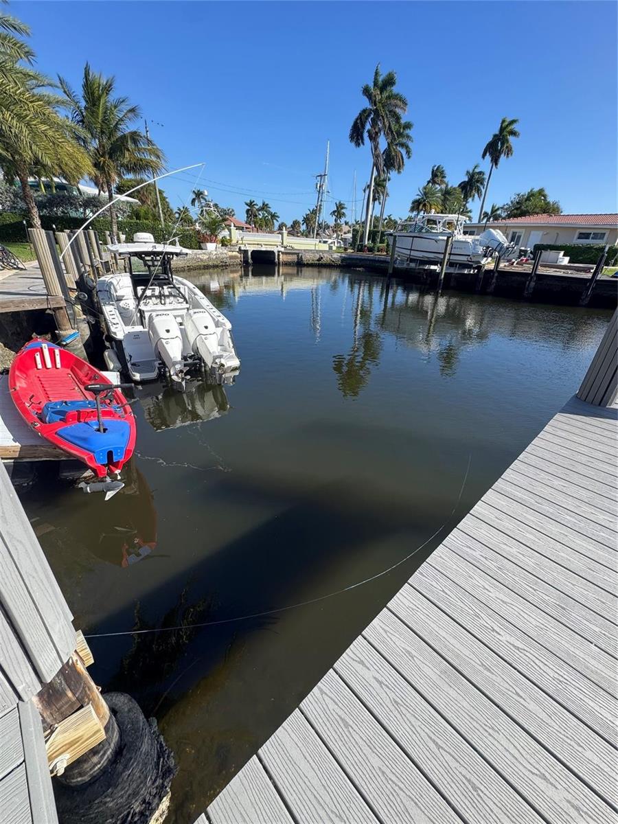 A canal view features a wooden dock, a red kayak, and two boats moored nearby — 840 SE 22nd Avenue, Pompano Beach FL 33062, POMPANO BEACH, FL