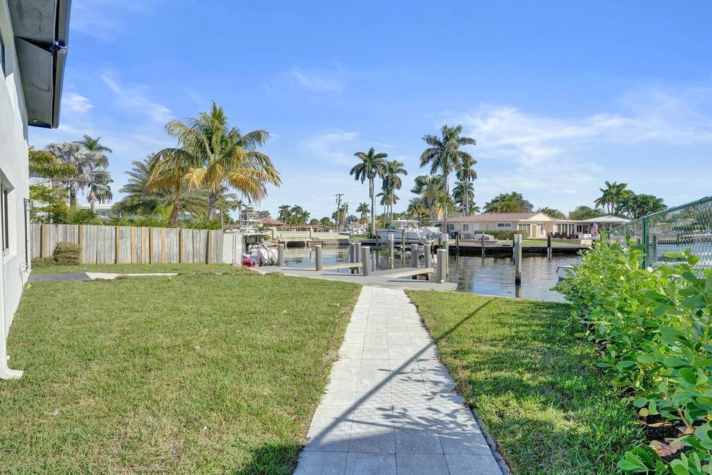 A backyard with a stone walkway leading to a private boat dock on a canal — 840 SE 22nd Avenue, Pompano Beach FL 33062, POMPANO BEACH, FL