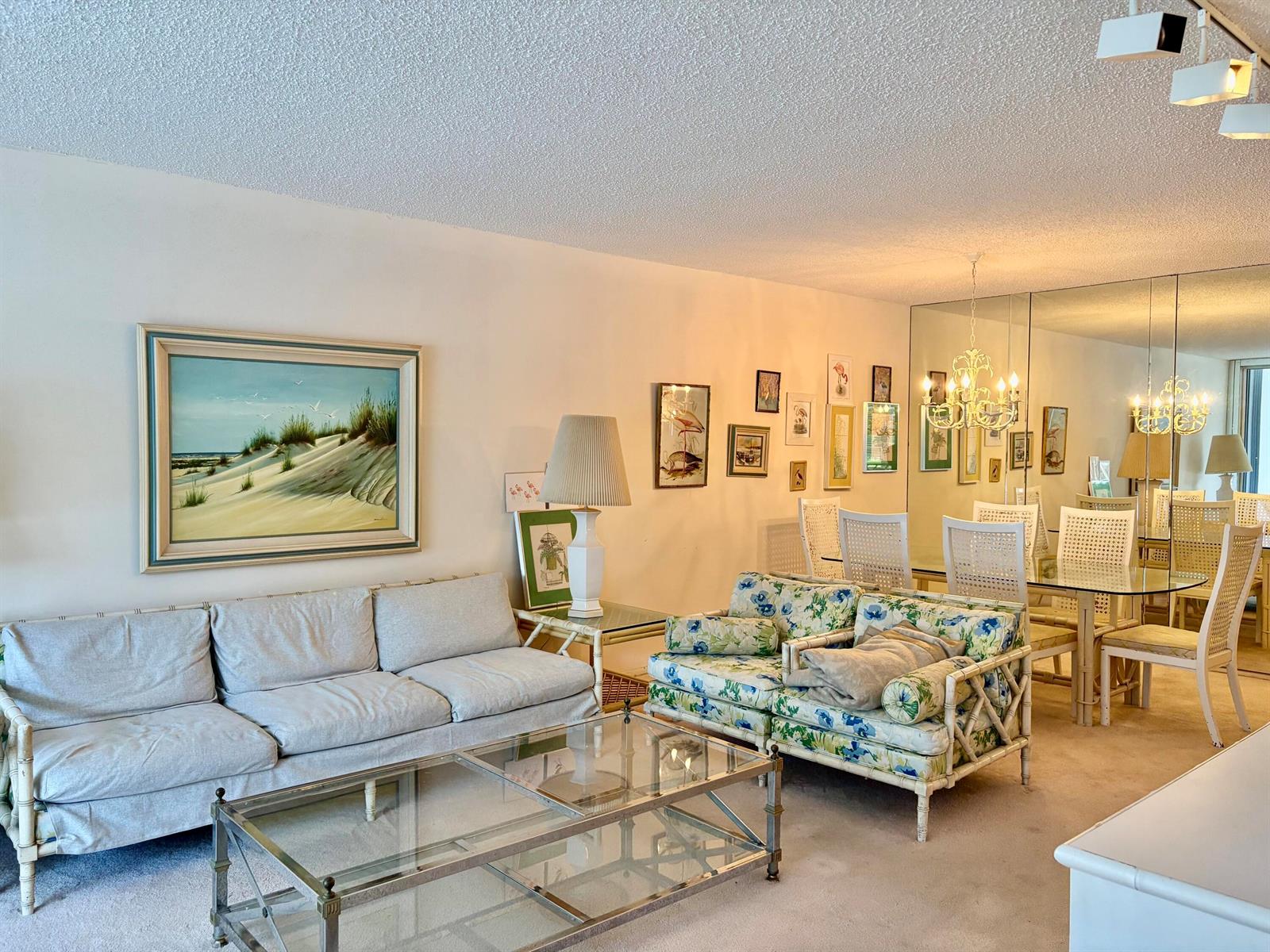 A living and dining room with a sofa, floral loveseat, glass coffee table, and mirrored wall — 3150 N Course Lane # 202, Pompano Beach FL 33069, POMPANO BEACH, FL