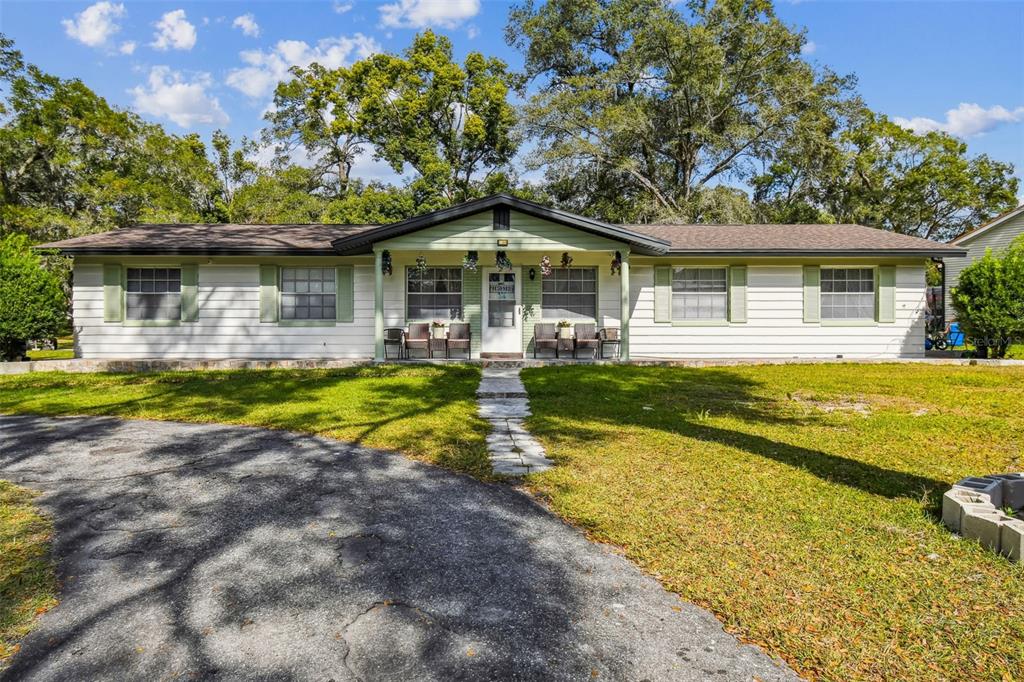 A single-story house with white siding, green shutters, and a covered front porch — 25309 CARNOUSTIE DRIVE, SORRENTO, FL