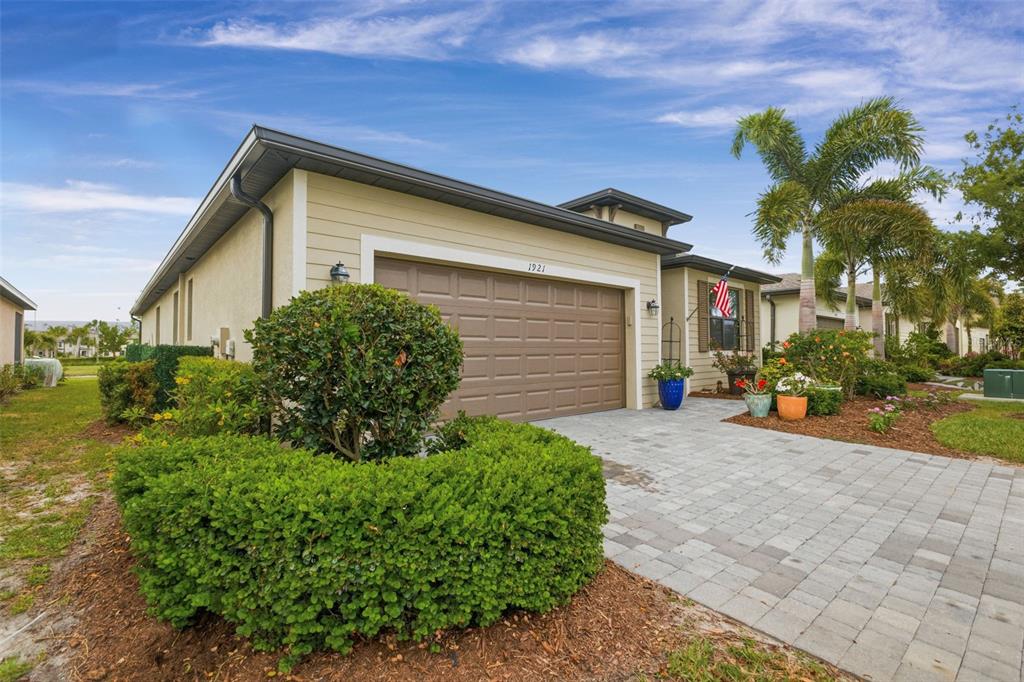 A beige house with a brown garage door and a paved driveway under a blue sky — 1921 E ISLES ROAD, PORT CHARLOTTE, FL