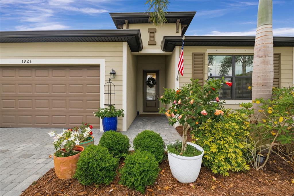 The exterior of a single-story house features a garage, a front entryway, and potted plants — 1921 E ISLES ROAD, PORT CHARLOTTE, FL