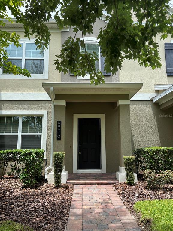 The exterior of a two-story townhouse features a covered entryway with a brick walkway — 8019 JEREMY JOSEPH ALLEY, WINTER GARDEN, FL