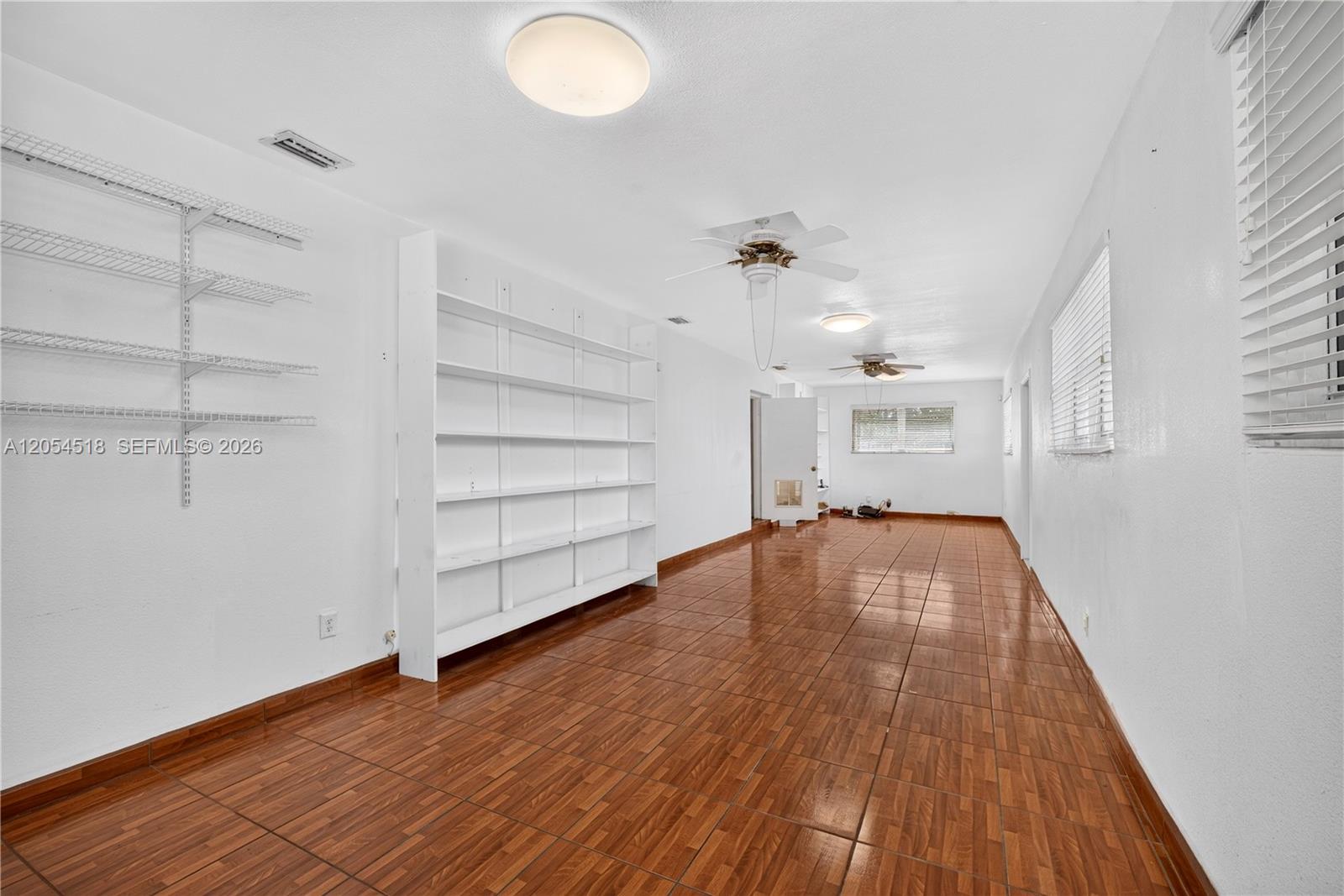 A long, narrow room features white walls, tile flooring, built-in shelving, and two ceiling fans — 12021 SW 174th St, Miami FL 33177, MIAMI, FL