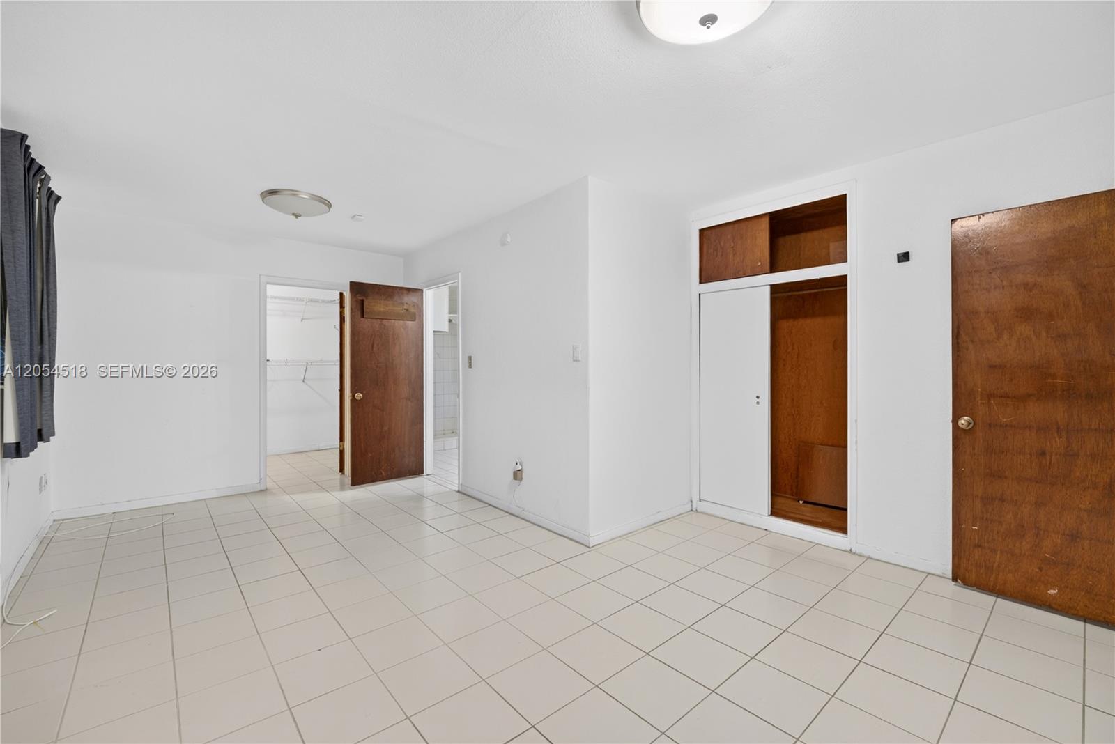 This bedroom features white walls, tiled flooring, a walk-in closet, and built-in wooden storage — 12021 SW 174th St, Miami FL 33177, MIAMI, FL