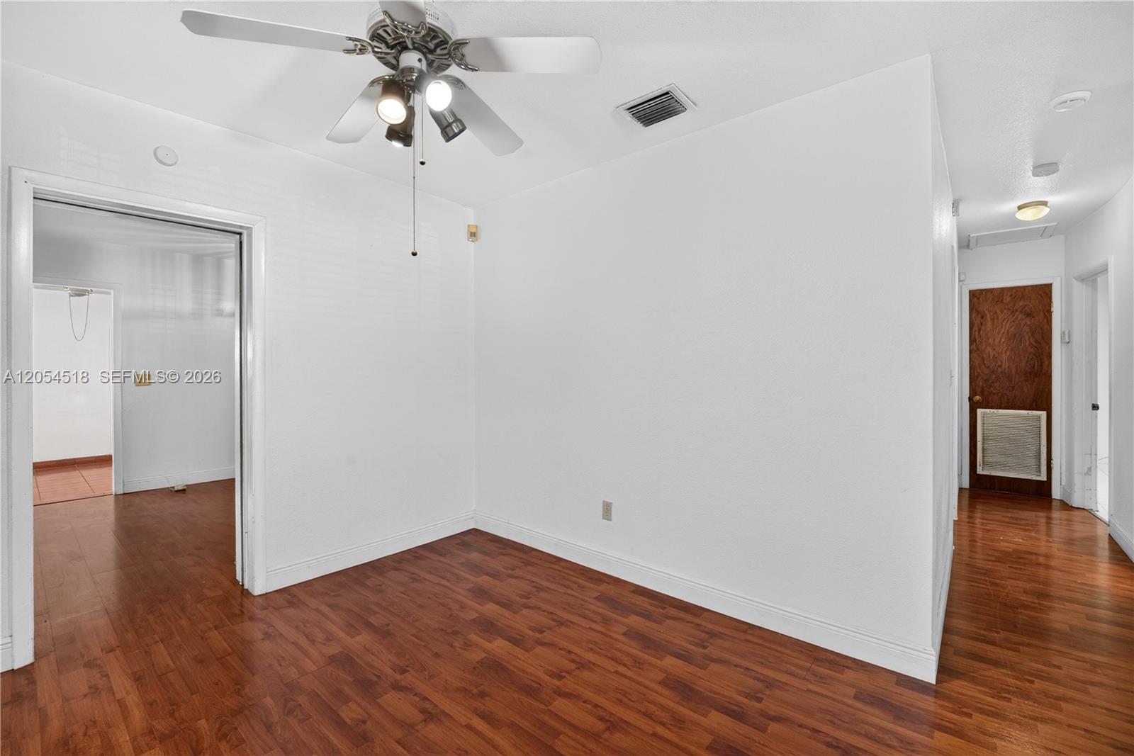 An empty room features white walls, dark wood-look flooring, and a ceiling fan — 12021 SW 174th St, Miami FL 33177, MIAMI, FL
