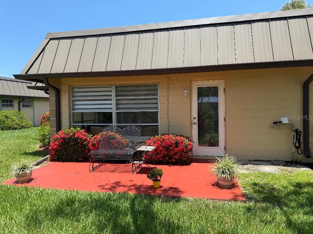 A red concrete patio sits in front of a tan building with a metal roof — 4142 HAMPTON DRIVE UNIT 4142, NEW PORT RICHEY, FL