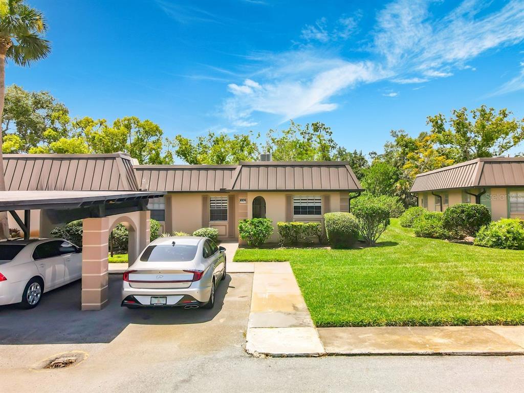 A single-story house with a metal roof, a carport, and a front lawn — 4142 HAMPTON DRIVE UNIT 4142, NEW PORT RICHEY, FL