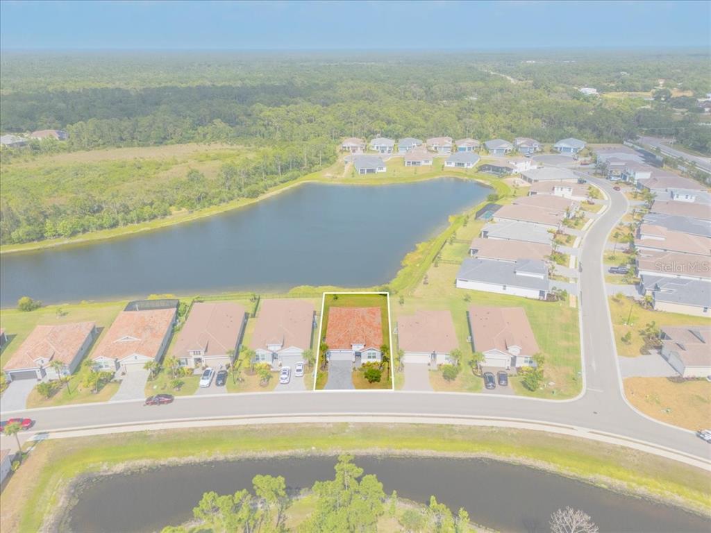 An aerial view shows a single-family home with a highlighted lot bordering a lake — 188 DAYLILY BOULEVARD, NOKOMIS, FL