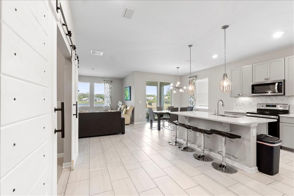 An open-concept kitchen and living area features a breakfast bar, light cabinetry, and tile flooring — 188 DAYLILY BOULEVARD, NOKOMIS, FL