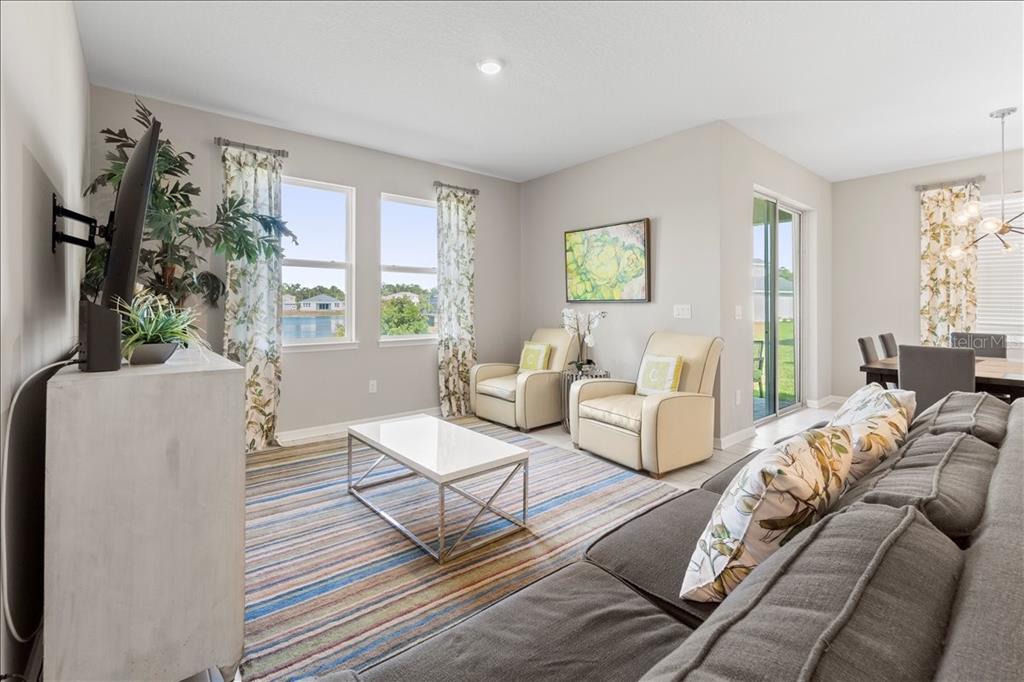 A living room with a gray sectional, two beige armchairs, and a white coffee table — 188 DAYLILY BOULEVARD, NOKOMIS, FL