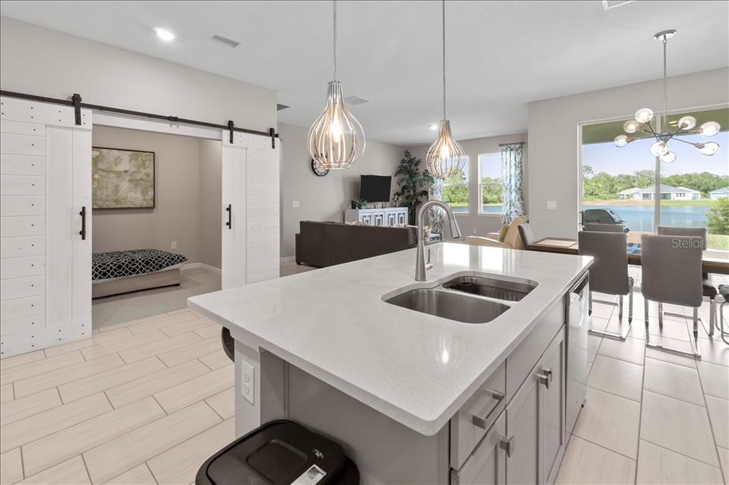 A kitchen island with a sink overlooks an open living area with sliding barn doors — 188 DAYLILY BOULEVARD, NOKOMIS, FL