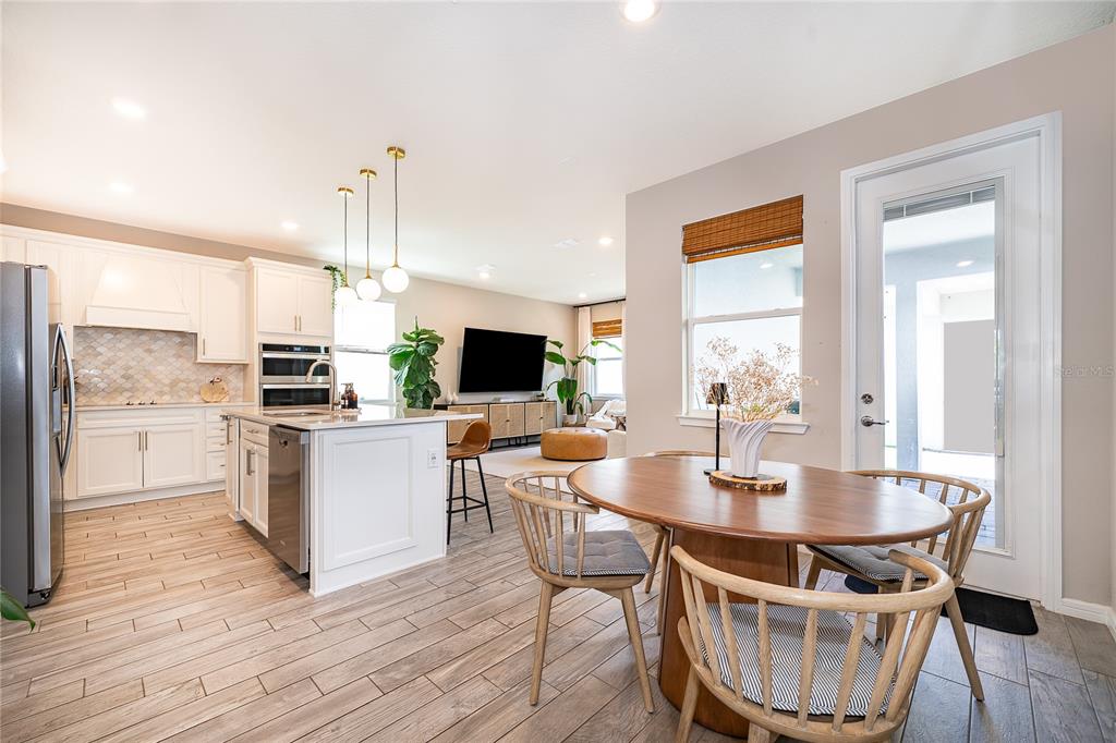 An open-concept kitchen and dining area features white cabinetry, a center island, and wood-look tile flooring — 14226 LANIKAI BEACH DRIVE, ORLANDO, FL
