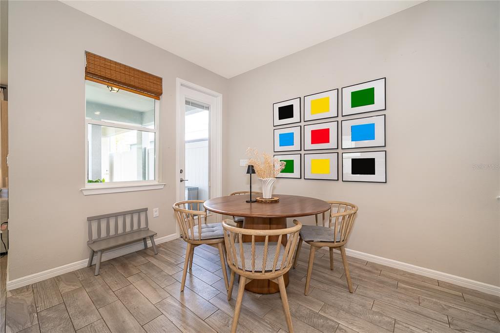 A dining area features a round wooden table, four chairs, a bench, and wall art — 14226 LANIKAI BEACH DRIVE, ORLANDO, FL