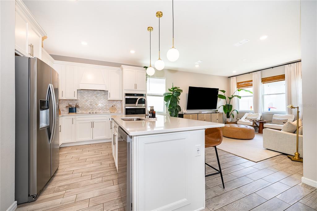 A modern kitchen with white cabinets and a central island opens into a living area — 14226 LANIKAI BEACH DRIVE, ORLANDO, FL