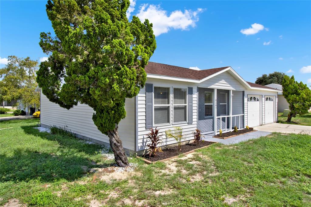 A single-story house with white siding, a gray brick facade, and a large front tree — 4241 ALAMANDA BOULEVARD, LAKE WALES, FL