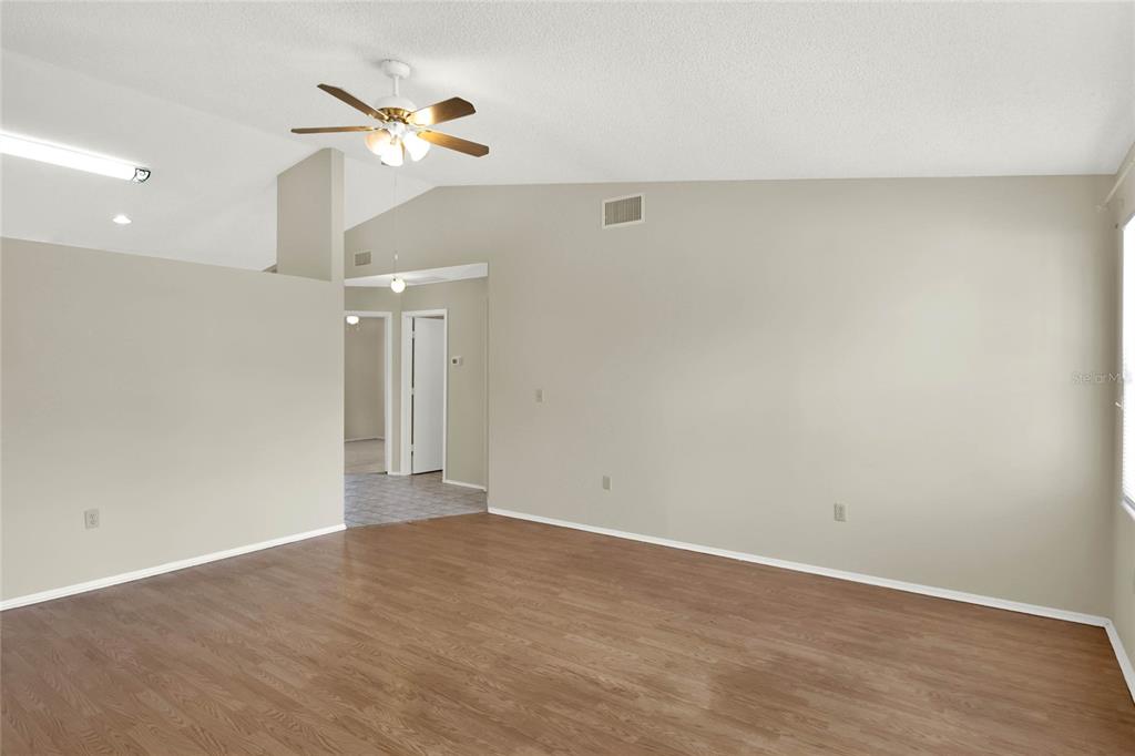 An empty living room features light-colored walls, wood-look flooring, and a ceiling fan — 4241 ALAMANDA BOULEVARD, LAKE WALES, FL