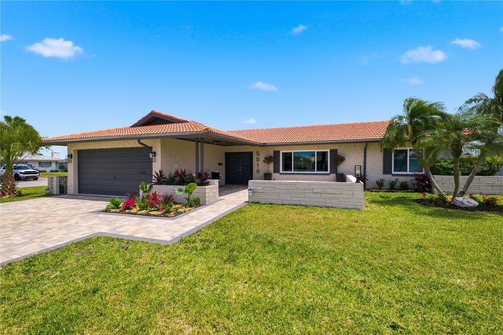 A single-story house with a tiled roof, gray garage, and a stone-walled front entryway — 5016 DORY DRIVE, NEW PORT RICHEY, FL