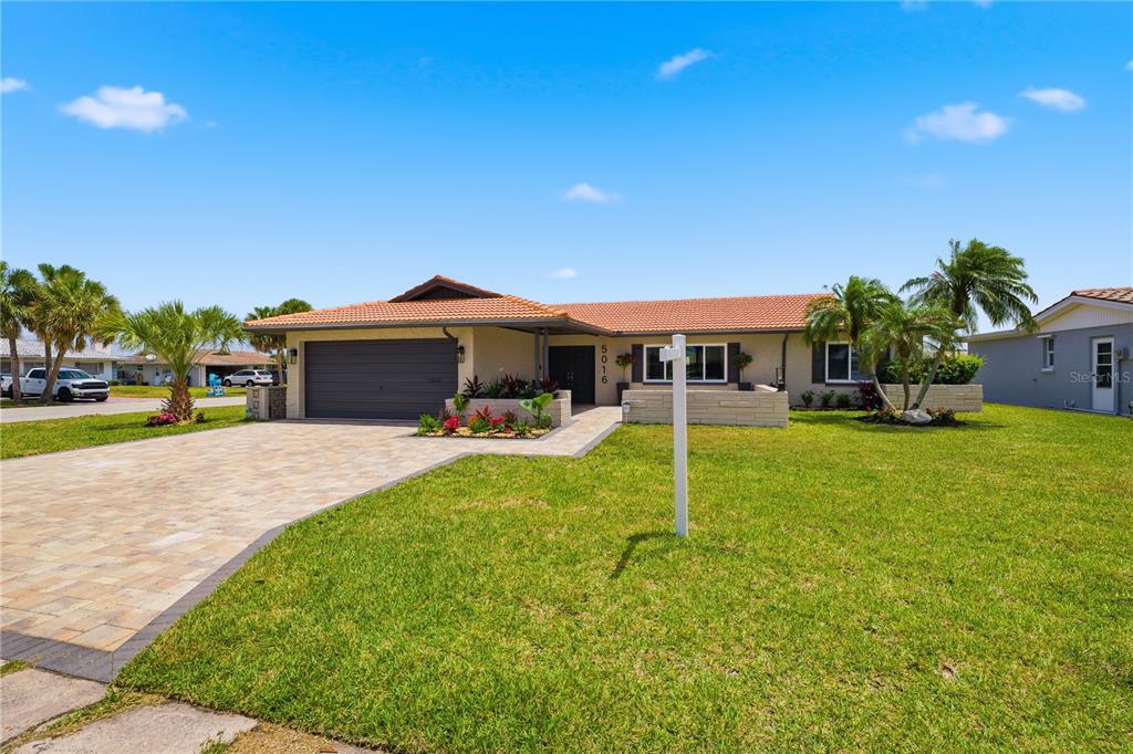 A single-story house with a tiled roof, a paved driveway, and a front lawn — 5016 DORY DRIVE, NEW PORT RICHEY, FL