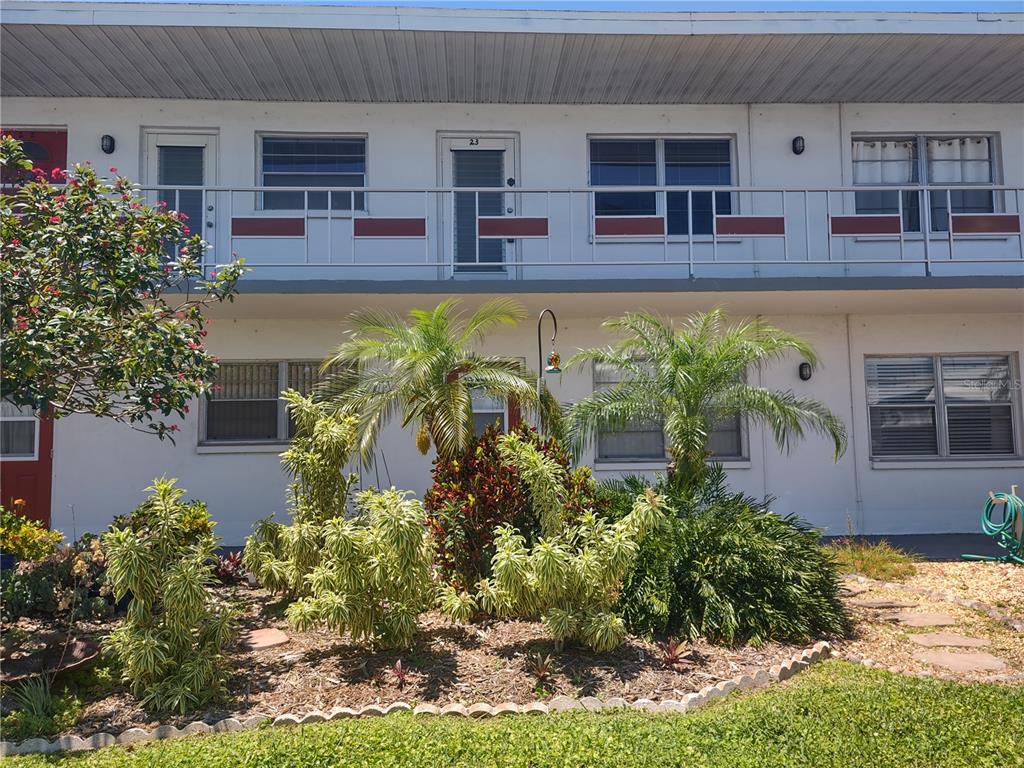 A two-story apartment building exterior features a balcony with metal railings and landscaped front gardens — 5850 18TH STREET N UNIT 23, ST PETERSBURG, FL