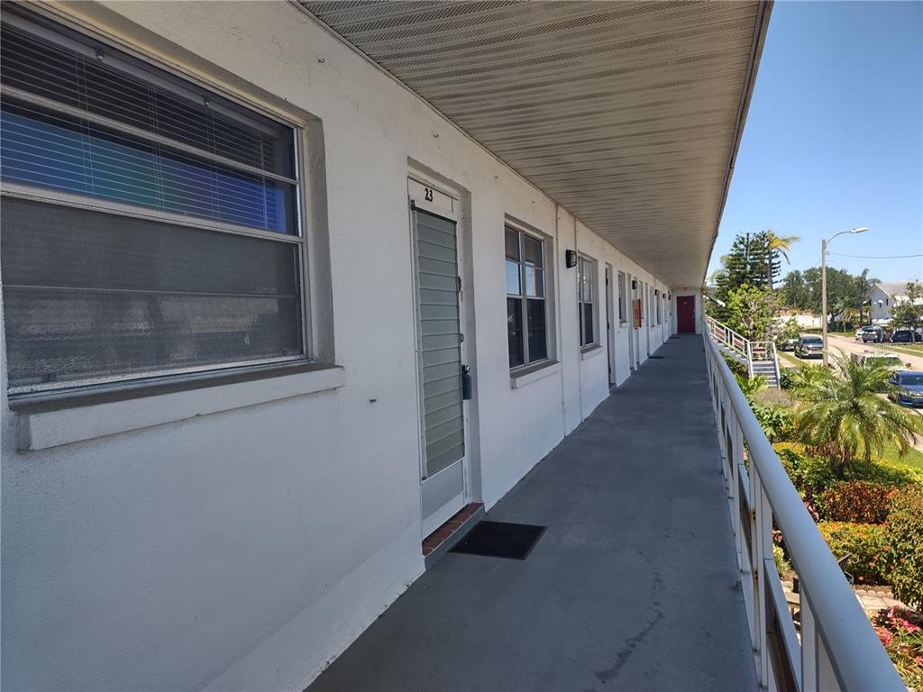 An exterior walkway with a white railing overlooks a street with parked cars and trees — 5850 18TH STREET N UNIT 23, ST PETERSBURG, FL
