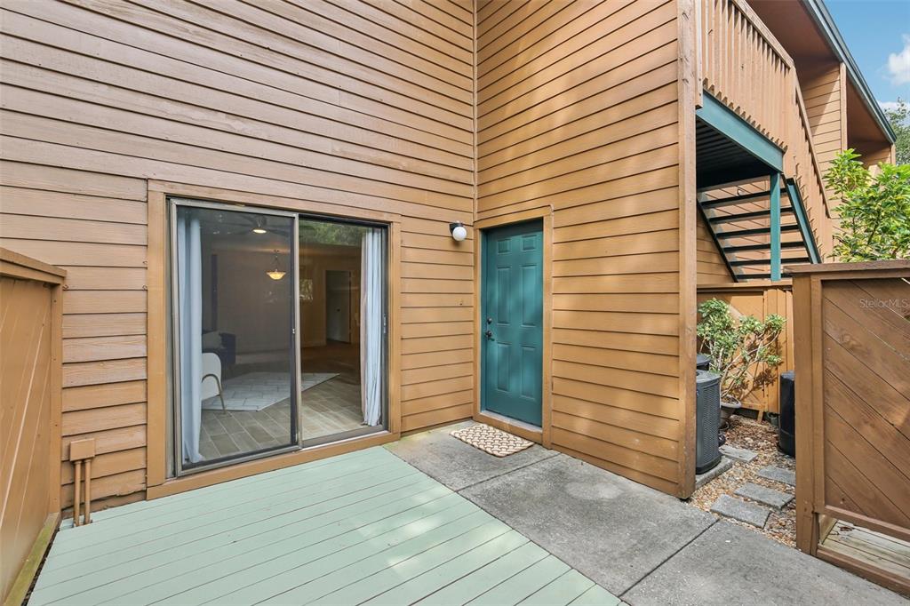 A wooden exterior features a sliding glass door, a green door, and a small deck — 2407 CYPRESS POND ROAD UNIT 2407, PALM HARBOR, FL