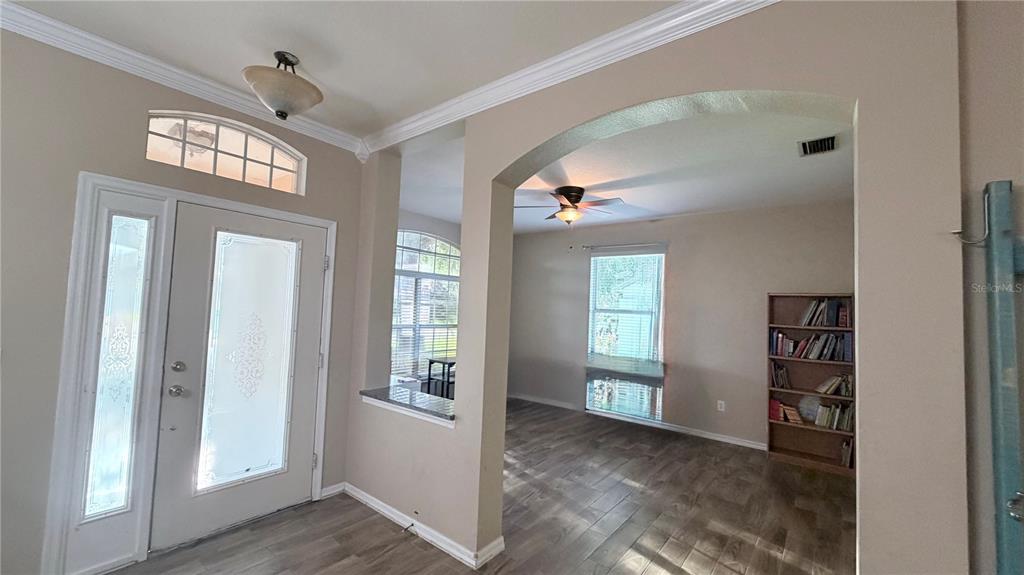 An entryway with a front door and arched opening leading to a room with bookshelves — 3806 TRIPLE JUMP STREET, VALRICO, FL