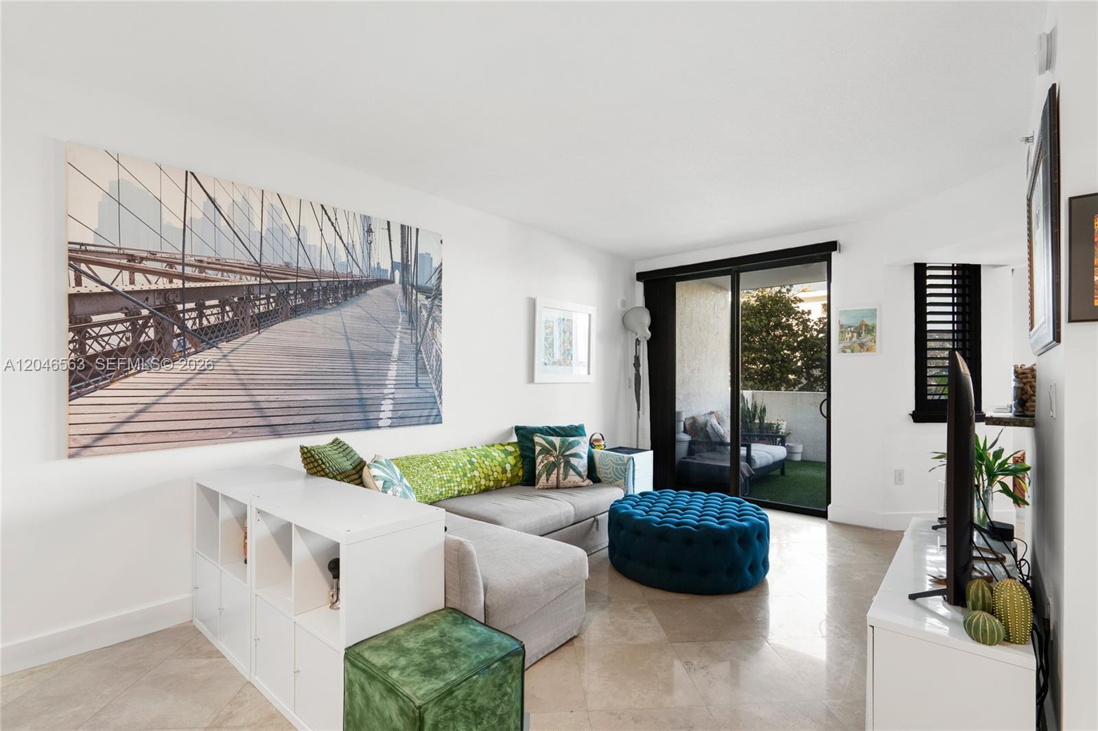 A living room features a gray sectional sofa, blue tufted ottoman, and a large bridge print — 110 Washington Ave # 2309, Miami Beach FL 33139, MIAMI BEACH, FL