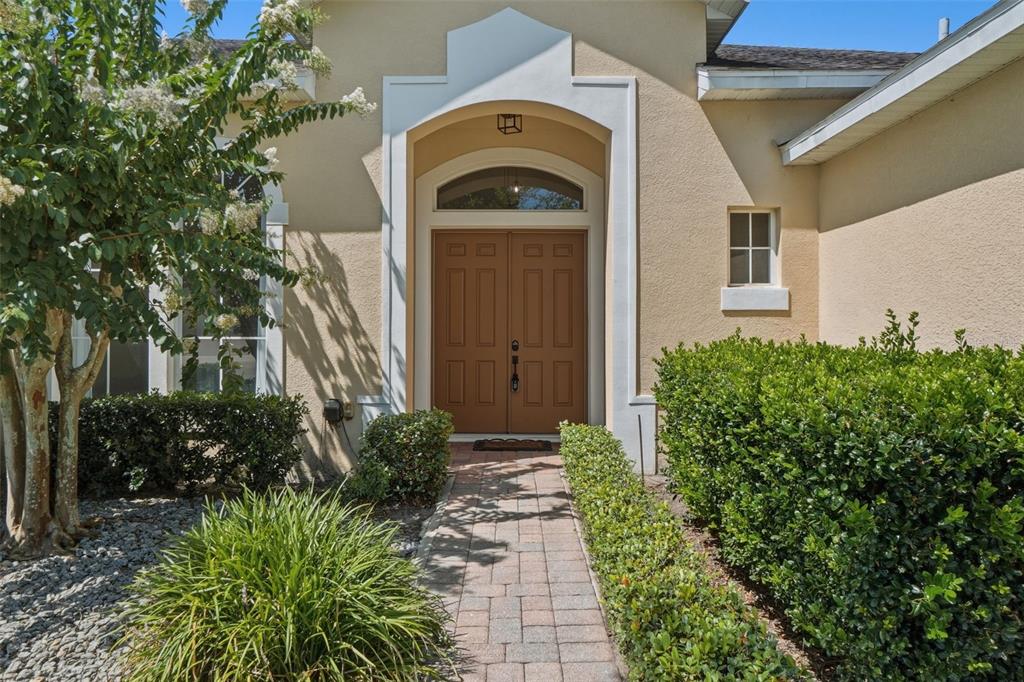 A paved walkway leads to the double front doors of a tan stucco house — 2330 PESARO CIRCLE, OCOEE, FL