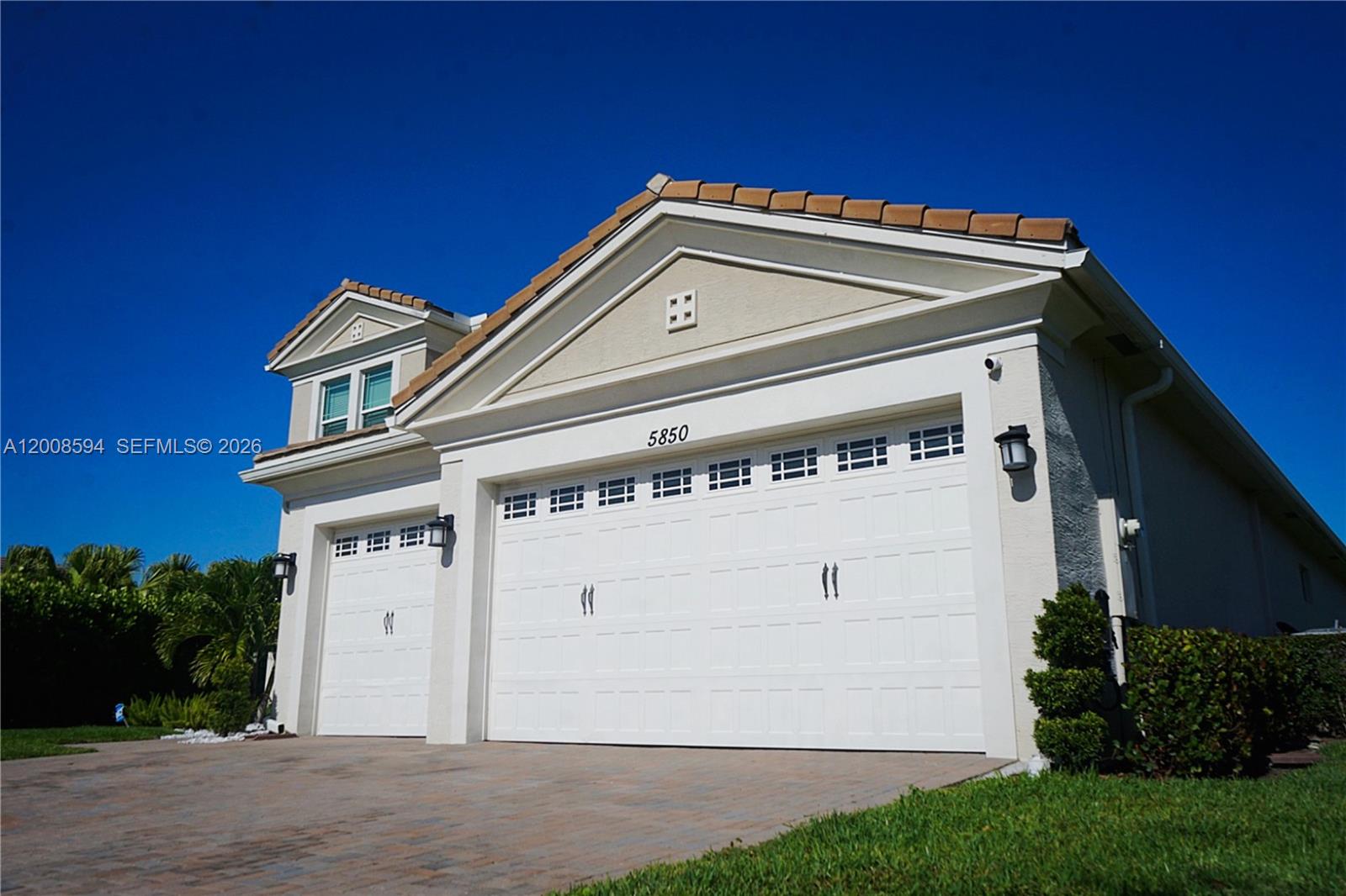 A two-story suburban house with a beige stucco exterior, a tiled roof, and a two-car garage — 5850 Whippoorwill Cir, Westlake FL 33470, WESTLAKE, FL