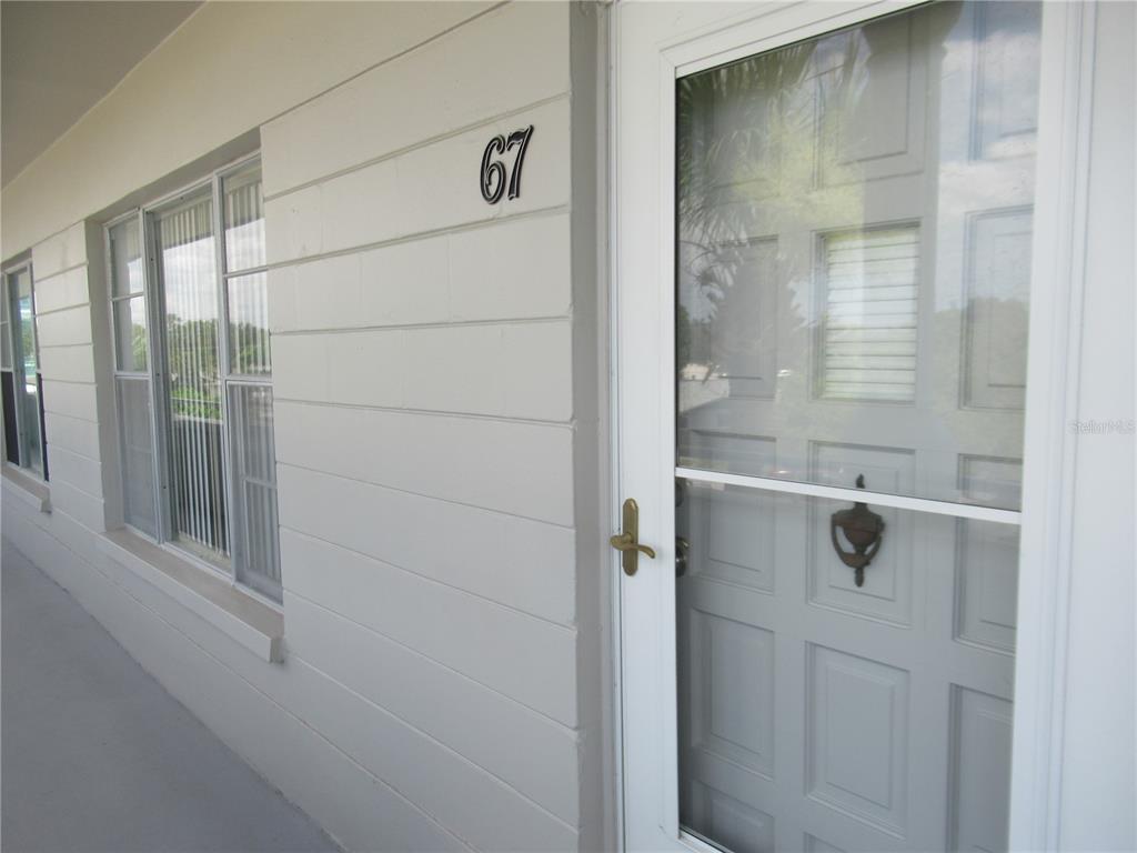 A light-colored exterior wall with the number 67 and a white front door — 2371 ISRAELI DRIVE UNIT 67, CLEARWATER, FL